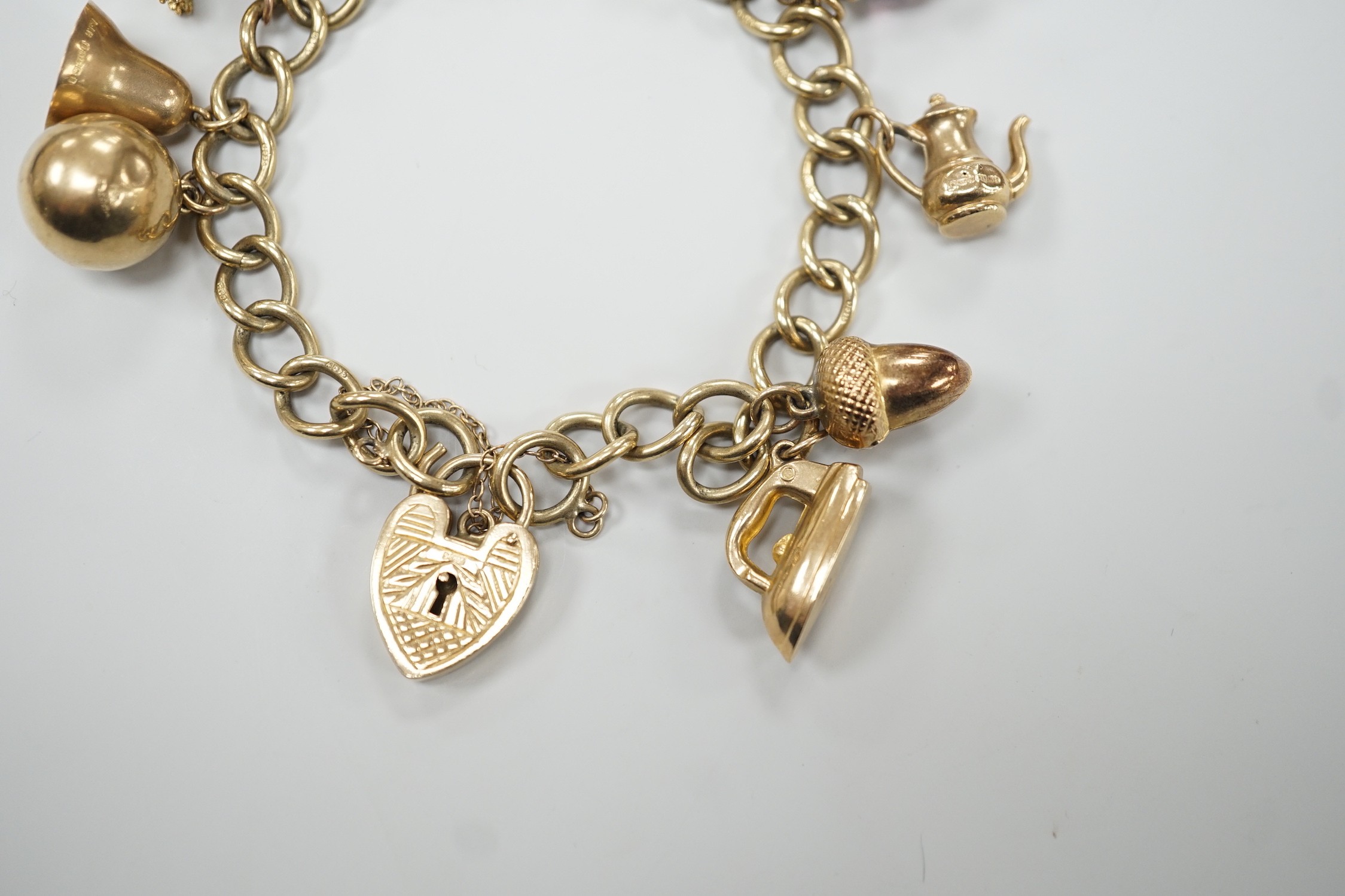 A 9ct gold oval link charm bracelet, hung with ten assorted charms including nine 9ct gold, gross weight 31.9 grams.
